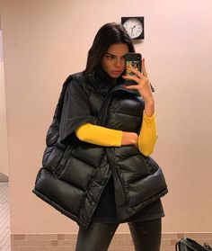 a woman taking a selfie with her cell phone in front of a wall clock