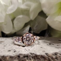 a diamond ring sitting on top of a piece of wood with flowers in the background