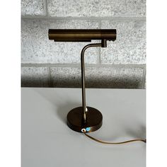 a lamp that is on top of a white table next to a brick wall and floor