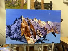 an easel with a painting of mountains on it