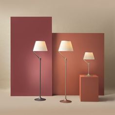 three lamps are standing next to each other in front of an orange and pink wall