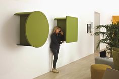 a woman is leaning against the wall and talking on her cell phone while holding onto a green shelf