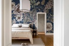 a bed sitting in a bedroom next to a wall with flowers painted on the walls