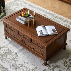 a coffee table with an open magazine on top and fruit in the middle sitting on it