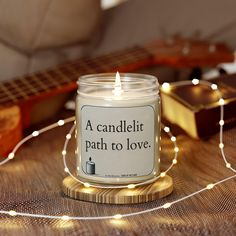 a candle sitting on top of a wooden table next to a guitar and string lights