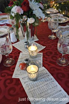 the table is set for christmas dinner with red and white flowers in vases on top