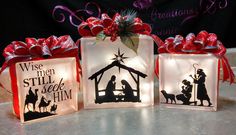 three lighted christmas gift bags sitting on top of a table with red bows around them