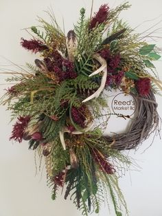 a wreath with red and green flowers on the front of it, hanging from a wall