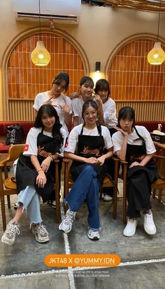 a group of young women sitting next to each other in front of a wooden table