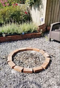 an outdoor fire pit surrounded by gravel and plants