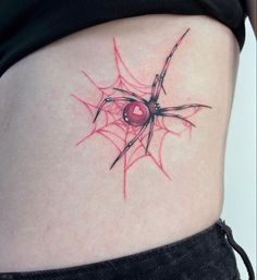 a spider web tattoo on the side of a woman's stomach, with a red ball in it