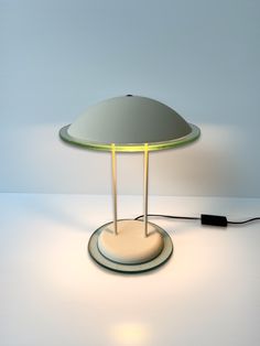 a lamp that is on top of a white table with a black cord attached to it