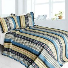 a bed covered in a blue and yellow plaid quilt next to a white headboard