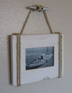 an old photo hanging on a rope with a boat in the water and a sailboat tied to it