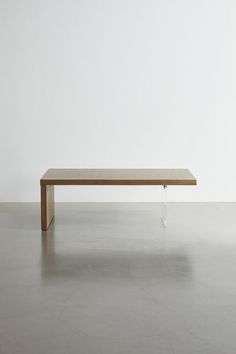 a wooden table sitting on top of a cement floor next to a white wall in an empty room