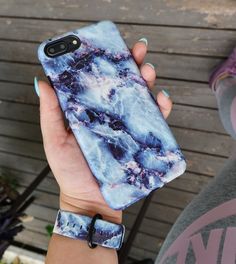 a woman is holding up her phone case with blue and white marble design on it