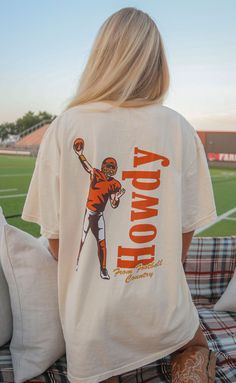 Say HOWDY! from football country in this off-white tee complete with a vintage inspired illustration of a quarterback mid pass! We love the red and yellow colorway of this design. 


Haley is 5'6" and is wearing size medium

Maggie is 5'4" and is wearing an XL for an oversized look


sizing guide: 


fits true to size - size up for an oversized fit

medium measurements: 41" bust and 28.5" length

100% cotton


WE ONLY OFFER STORE CREDIT FOR RETURNS! Feel free to email us at orders@shopriffraf Vintage College Football Shirts, Country T Shirt Designs, Game Day T Shirts, College Shirt Ideas, Spirit Wear Designs, Off White Tees, Cricket T Shirt, Football Apparel, Tri Delt