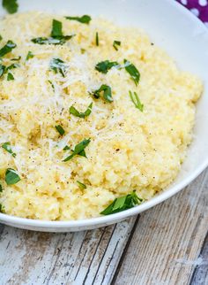 a white bowl filled with riso and parmesan cheese on top of a wooden table