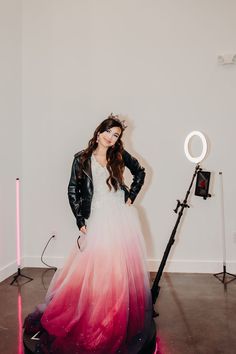 a woman in a pink and white dress is standing next to a light with her hands on her hips