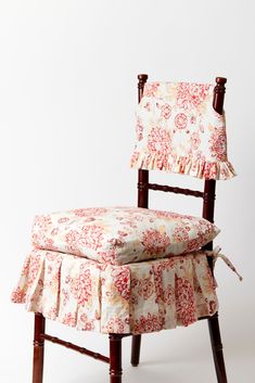 an upholstered chair with a flowered seat cover and ruffled skirt on it