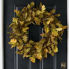 a wreath hanging on the front door of a house with black doors and white trim