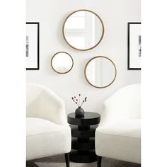 three round mirrors mounted on the wall above a table with two chairs and a vase