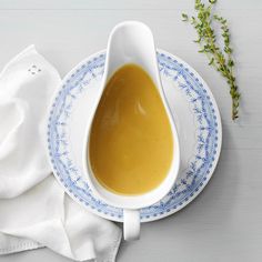 a bowl of soup on a plate next to a napkin and green sprig