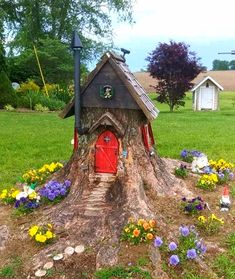 a tree stump with a house built into it and flowers growing out of the base