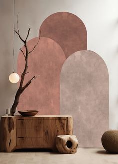 a tree in front of a wall with pink and grey shapes on it, next to a vase