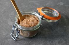 a jar filled with brown sugar next to an orange handled spoon on top of a table