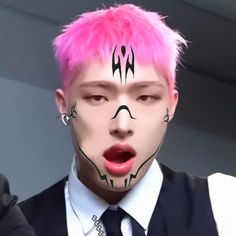 a man with pink hair and face paint making a funny face while wearing a vest