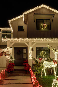 a house decorated for christmas with lights and reindeer decorations on the front yard, along with holiday wreaths