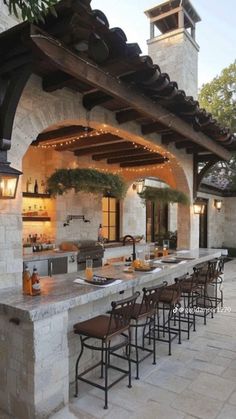 an outdoor kitchen with lots of counter space and lights hanging from the roof over it