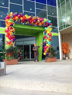 a man standing in front of a building with a giant arch made out of balloons