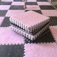 three pieces of pink and black rugs on the floor next to a vase with flowers