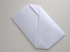 an origami paper airplane on a white surface with one end folded up to the side