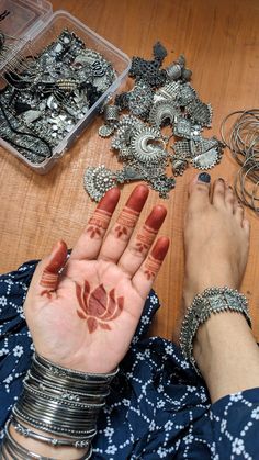 a woman's hands with hendix and bracelets on the floor next to jewelry