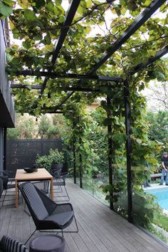 an outdoor patio with chairs and tables under a pergolated roof over a pool