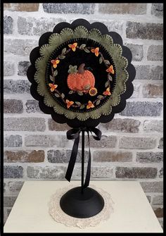 a decorative black and orange pumpkin decoration on top of a white table next to a brick wall