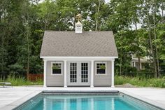 a small pool house next to a swimming pool