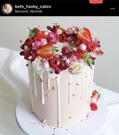 a strawberry cake with white icing and flowers on top