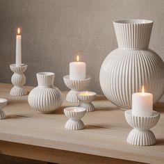 a table topped with white vases and candles