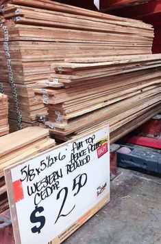 a pile of wood sitting on top of a wooden floor next to a sign that says $ 2 00