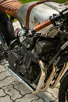 a close up of a motorcycle parked on a street with grass in the background and cobblestone pavement