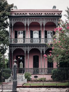 an old pink house with wrought iron fence