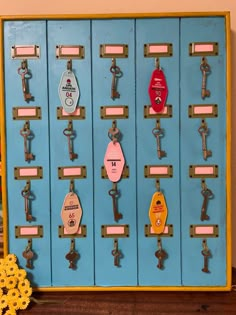 a bunch of keys are hanging on a blue cabinet with yellow flowers in the corner