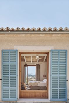 an open door leading to a bedroom with blue shutters