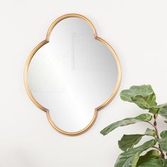 a mirror sitting on top of a table next to a potted plant and a white wall