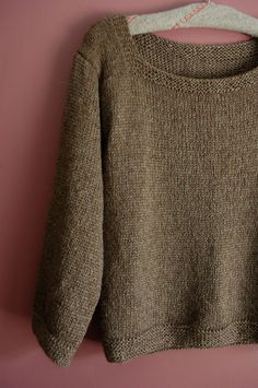 a brown sweater hanging on a pink wall