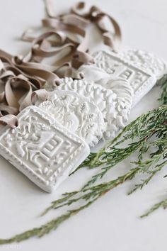 three different types of decorative items on a white surface with brown ribbons and greenery